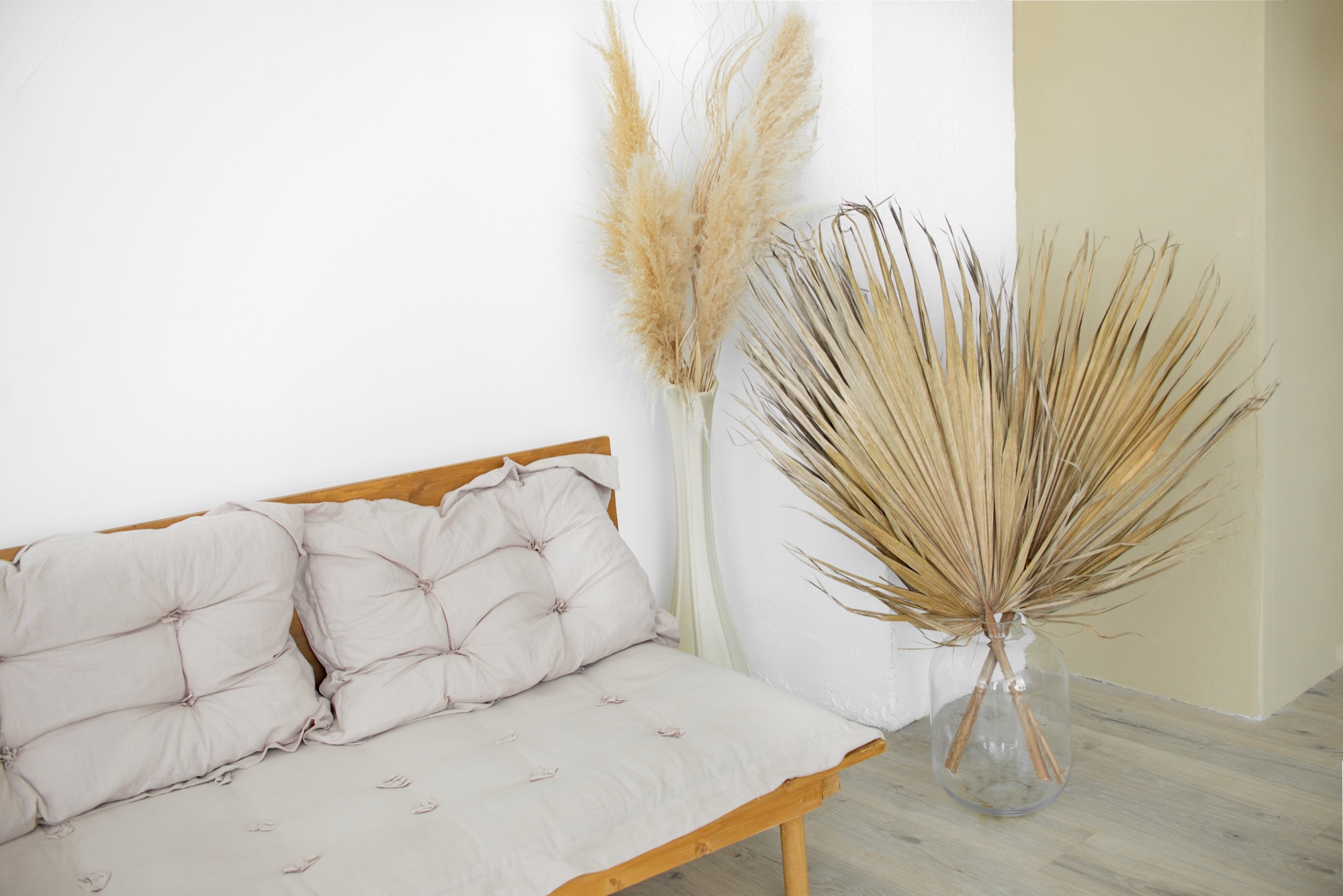A calm room with a wooden bench, linen cushions and dried grasses